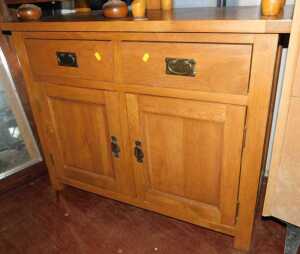 A light oak chest, of two drawers over two panelled doors, raised on square supports.