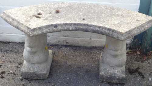 A part circular reconstituted stone bench.