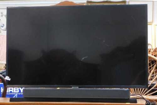 A Samsung 43" flat-screen television, model no. UE43NU7400U, with remote and a soundbar.