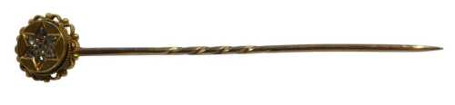 A diamond set stick pin, the circular pin head set with seven round brilliant cut diamonds, each...