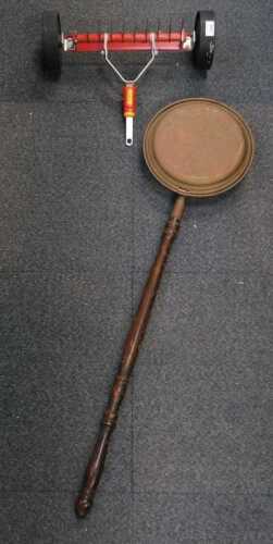 A garden scarifier, and a brass warming pan with wooden handle.