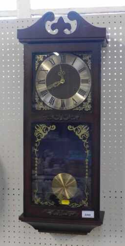 A modern wall clock, with Roman numerals to dial, and pendulum.