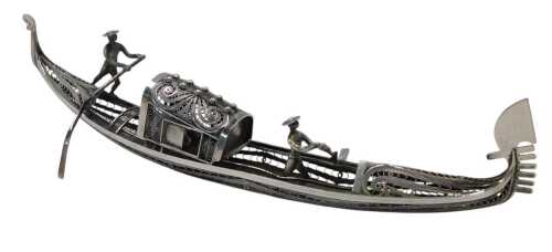 A white metal filigree model of a gondola, surmounted by two figures with paddles, white metal...