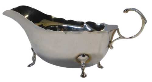 An Elizabeth II silver sauce boat, with a pie crust border and open handle, raised on three hoof...
