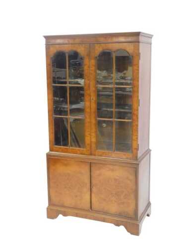 A 20thC burr walnut cabinet bookcase, with moulded cornice, two astragal glazed doors, two-door...