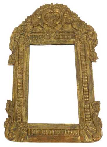A heavily carved gilt wood mirror, the surround surmounted by scrolls and flowerheads with...