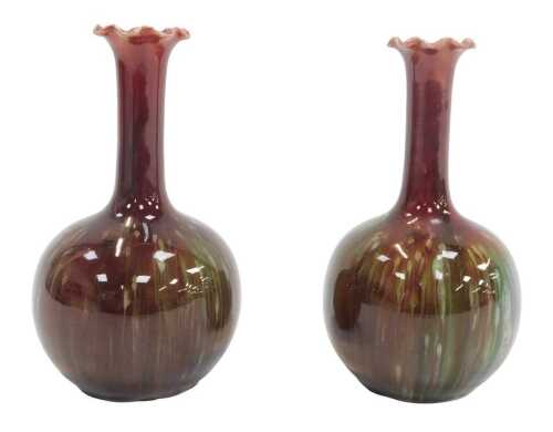 A pair of Burmantofts pottery bottle-shaped vases, each with a waved border, in a mottled green...