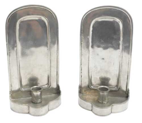 A pair of Continental pewter wall-mounted candle holders, each with a raised arch back and a...
