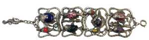 A contemporary four-link bracelet, white metal and coloured art glass, cast as open panels of...