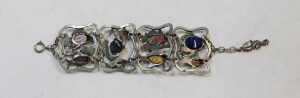 A contemporary four-link bracelet, white metal and coloured art glass, cast as open panels of... - 2