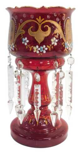A Victorian cranberry glass lustre, decorated in coloured enamels with floral swags and gilt...