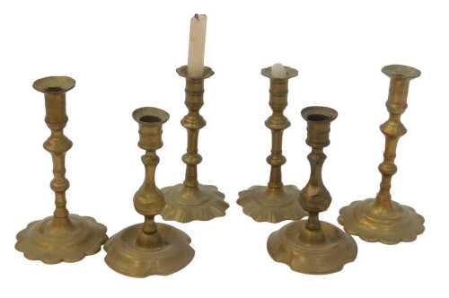 Two pairs of Georgian turned brass candlesticks, with petalated bases, and a further pair, the...