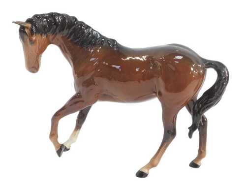 A Royal Doulton brown bay horse, modelled with one leg raised, 18cm high.