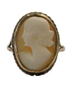 A shell cameo dress ring, quarter profile female facing sinister, in a rub over and pleated...