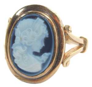 A 9ct gold blue agate carved cameo dress ring, in a raised rub over setting, with heavily scroll...