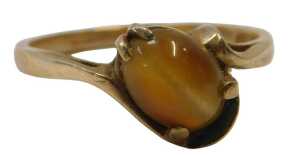 A tiger's eye dress ring, the oval-cut cabochon stone, in a four-claw mount setting, on a twist...
