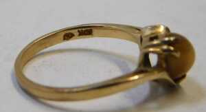 A tiger's eye dress ring, the oval-cut cabochon stone, in a four-claw mount setting, on a twist... - 2