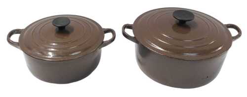 A Le Creuset brown enamel two-handled casserole dish and cover, 31cm wide, and a similar smaller...