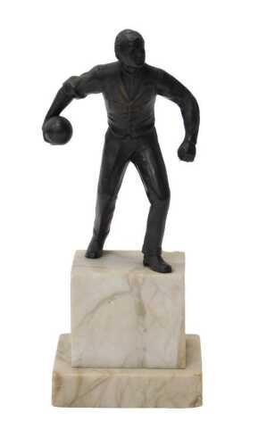 An early 20thC bronze patinated figure of a man with a bowling ball, on a marble plinth, 23cm high.