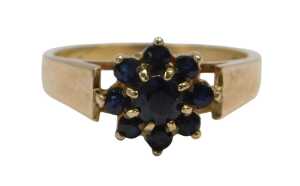 A 9ct gold cluster ring, set with nine dark blue sapphires, in a floral cluster setting,...