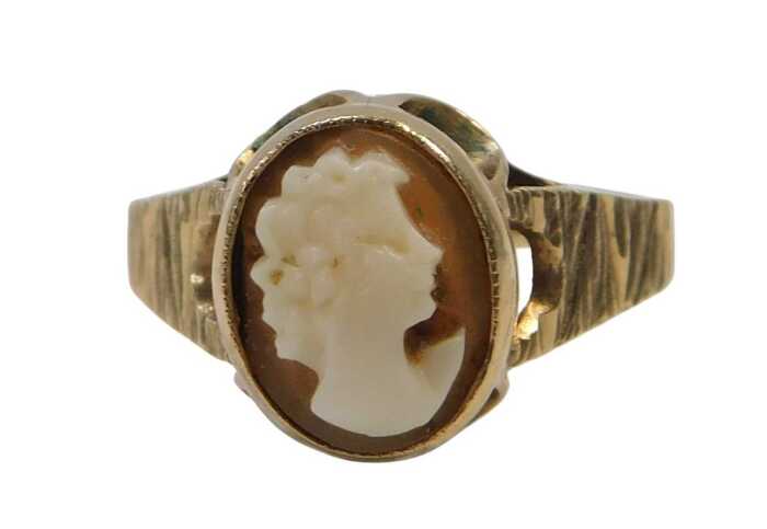 A 9ct gold shell cameo dress ring, the oval shell cameo in a rub over and petaled mount, on...