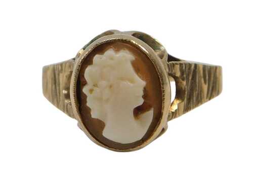 A 9ct gold shell cameo dress ring, the oval shell cameo in a rub over and petaled mount, on...