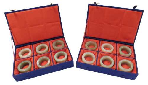 Two sets of six Oriental green hardstone napkin rings, each in a fitted case.