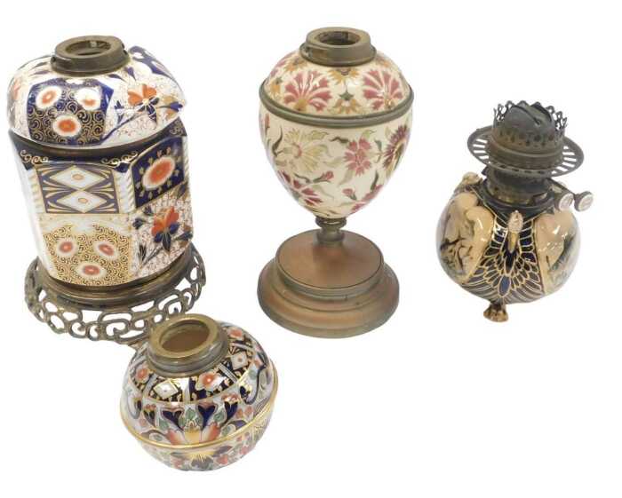 A group of oil lamp bases, to include a Zsolnay style pottery base, decorated with flowers, in...