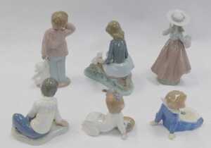 A group of Nao porcelain figures, to include a girl seated on a fallen tree trunk beside rabbits,... - 2