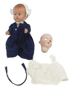 A mid 20thC composition doll, wearing a bonnet and blue dress with a pinny, 22cm high, together...