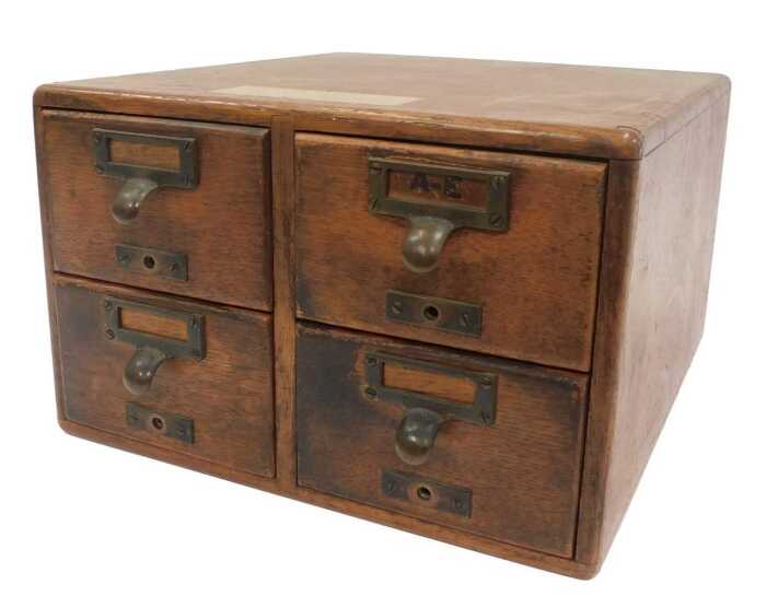 An early 20thC oak four-drawer tabletop filing cabinet, with metal lobed handles and integrated...