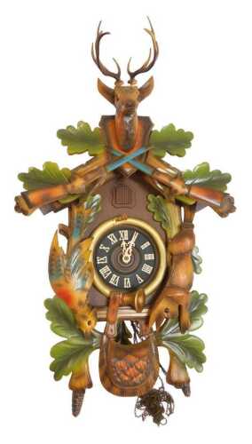 A West German Black Forest style part painted cuckoo clock, decorated with carved animals,...