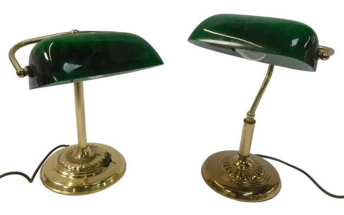 Two similar brass desk lamps, each with a green glass shade, raised on a circular, stepped and...