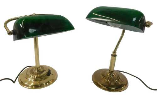 Two similar brass desk lamps, each with a green glass shade, raised on a circular, stepped and...