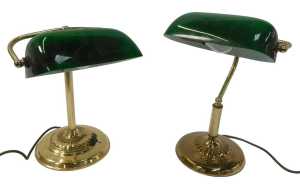 Two similar brass desk lamps, each with a green glass shade, raised on a circular, stepped and...