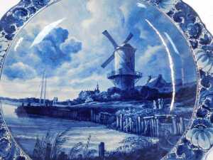 A 20thC Delft pottery charger, decorated centrally with a windmill before a river, within a... - 2