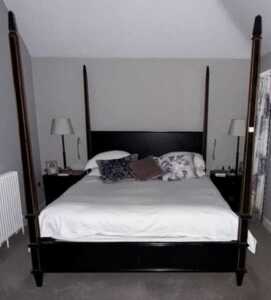 An ebonised four poster double bed, with bed base.
