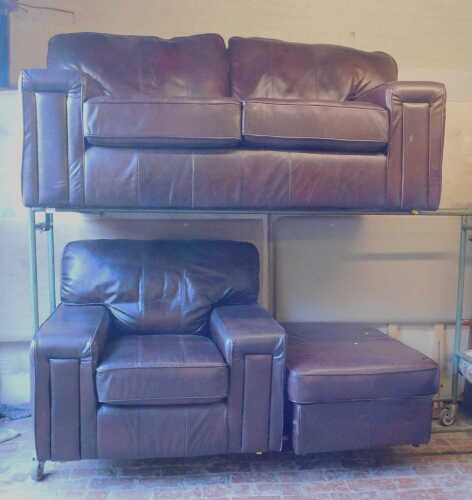 A brown leather sofa suite, comprising a two seater sofa, an armchair, and a footstool. (3)