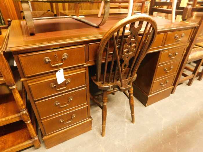An oak twin pedestal desk, the top inset with a faux burgundy tooled leather panel, above an...