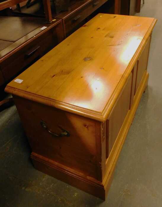 A pine blanket chest, with a panelled front and hinged top with a moulded edge, with two metal...