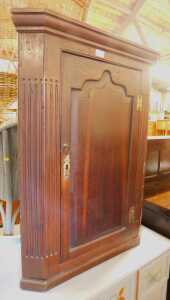 A George III oak hanging corner cabinet, with a moulded top over an arched moulded cabinet door,...