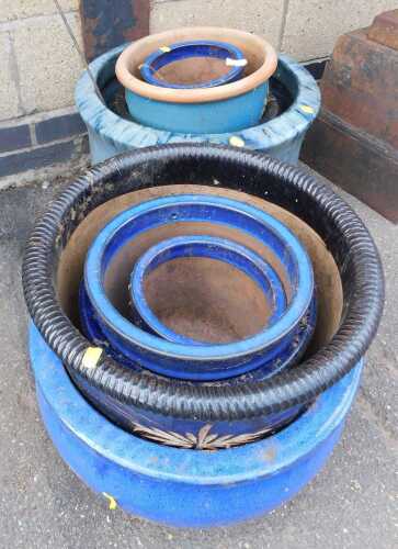 A group of blue and turquoise glazed plant pots, each of differing design and size, the largest...