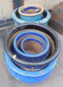 A group of blue and turquoise glazed plant pots, each of differing design and size, the largest...