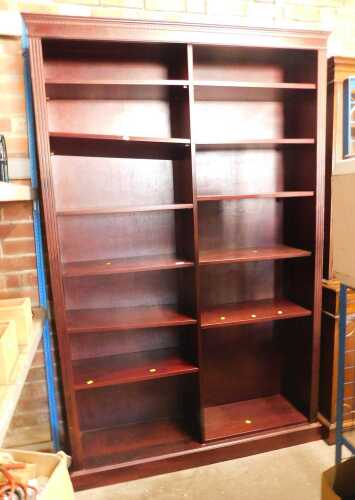 An open bookcase, of large proportion, in two sections, each with various shelves, raised on a...