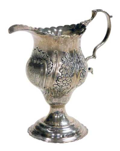 A George III silver cream jug, of ogee form, with a double scroll handle, the body embossed with...