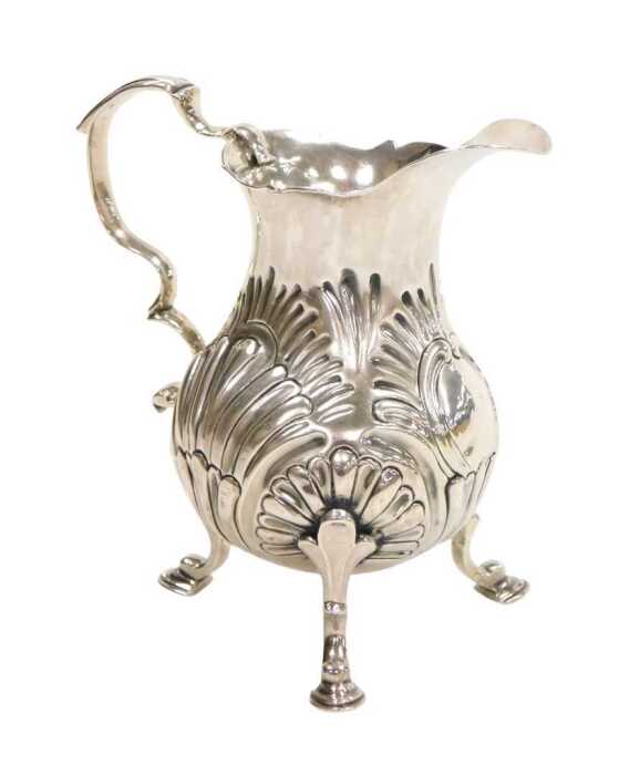 A George II silver cream jug, of pear shaped form, with a double scroll handle, embossed...