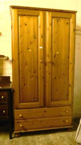 A pine double wardrobe, having two panelled doors enclosing a single hanging rail, with two...