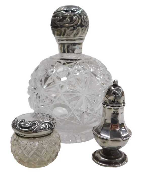 A Victorian cut glass scent bottle, with a silver mount and screw lid, embossed with flowers and...