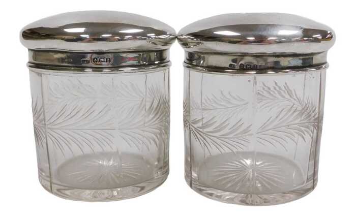 Two George V cut glass and silver lidded toilet jars, engraved with a band of leaves, Birmingham...