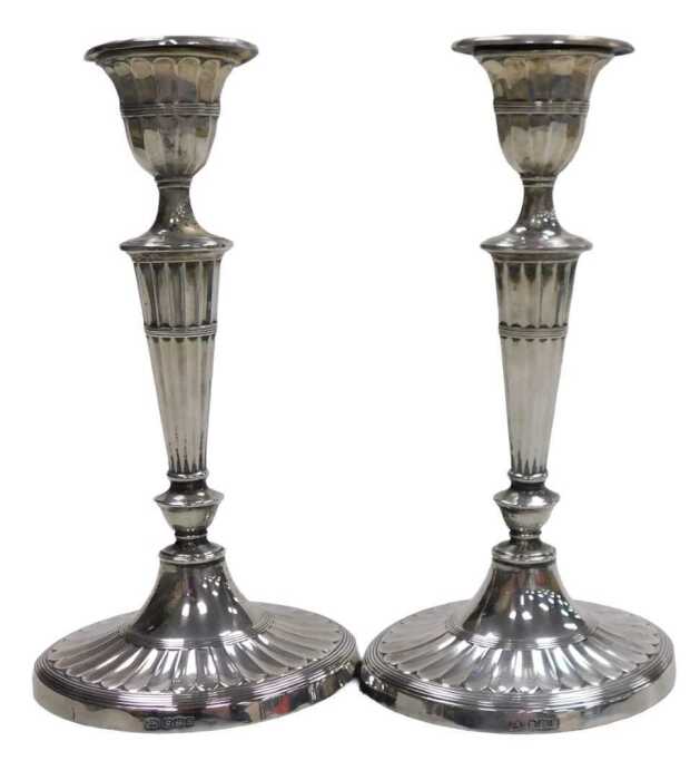 A pair of George V Adams style loaded silver candlesticks, of fluted form, raised on outswept...